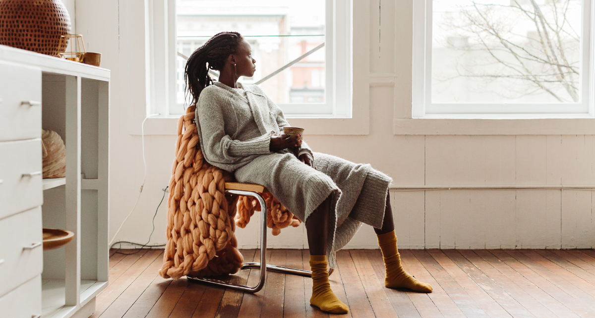 Woman sits on chair and looks out window looking lost