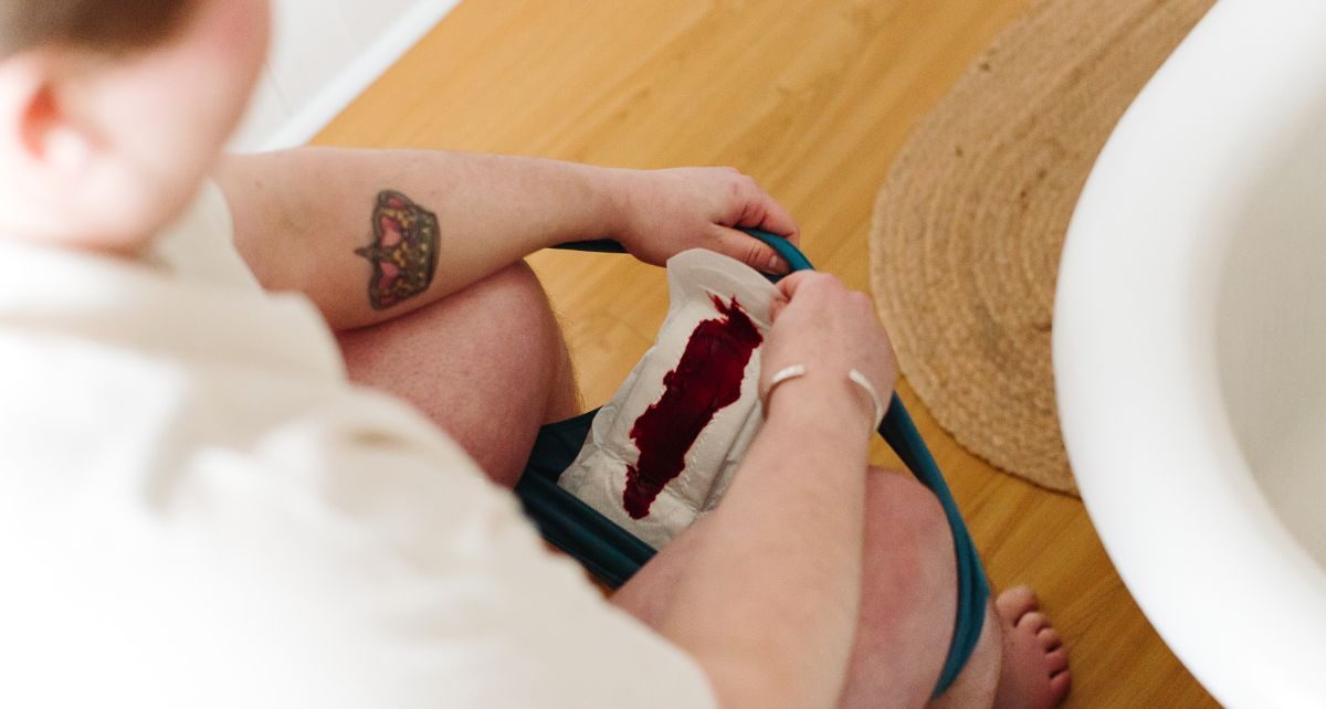 Person on toilet looks at blood soiled pad