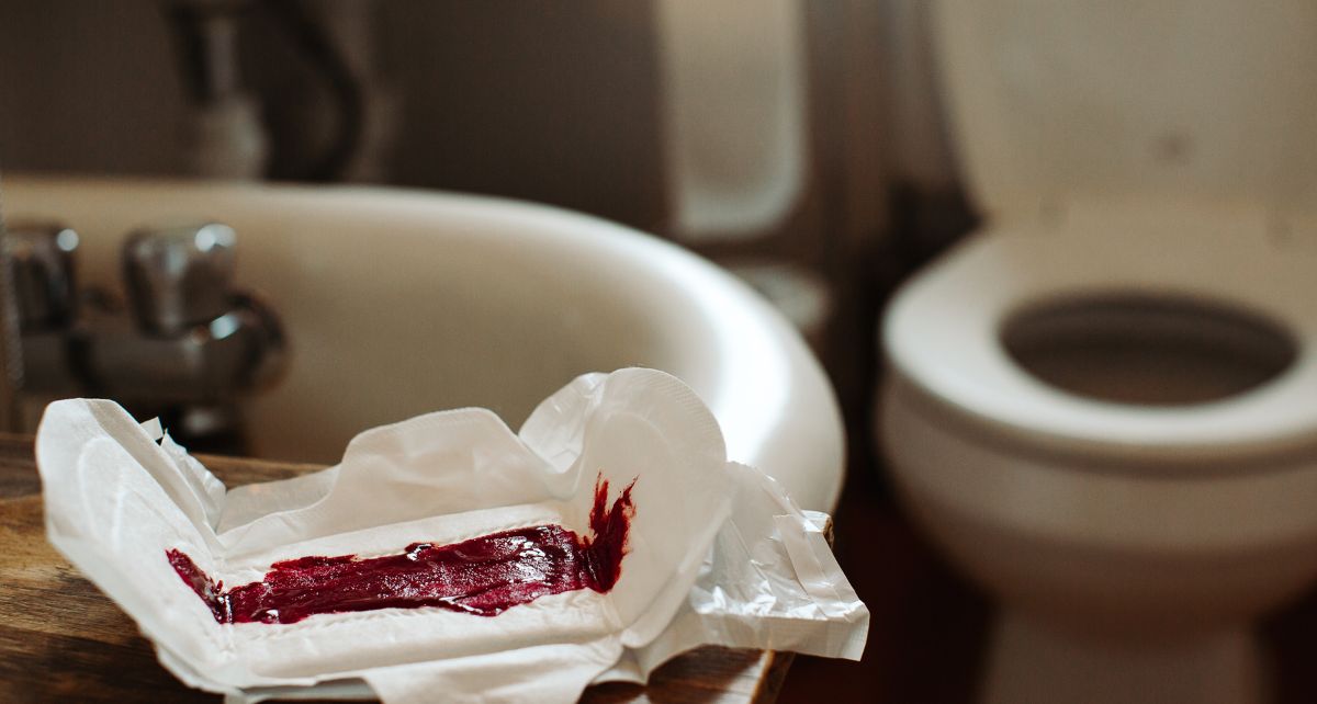 Period pad with menstrual blood on the edge of a bathtub