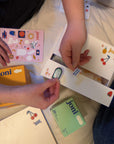 Hands organizing joni Retro Period Care Bundle with fun stickers and pads, showcasing nostalgic design.