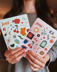 Person holding joni sticker sheets featuring retro designs for organizing period care products.