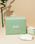 Green 'joni' box with packets on a beige background