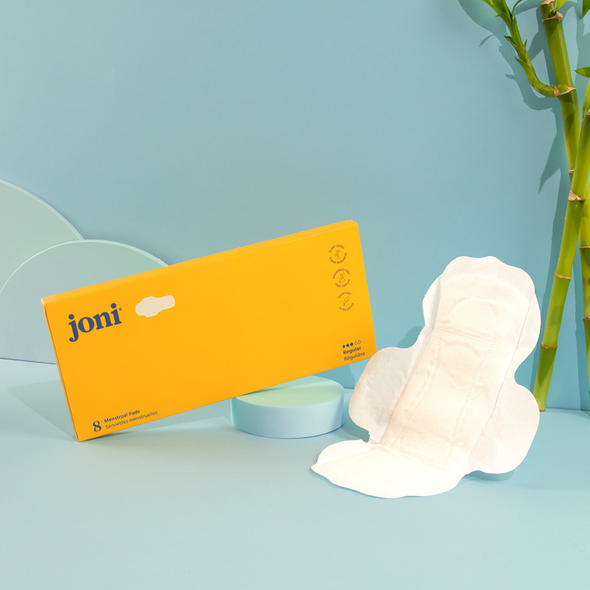 Joni Bamboo Regular Pads in yellow packaging with one pad displayed on a pastel background.