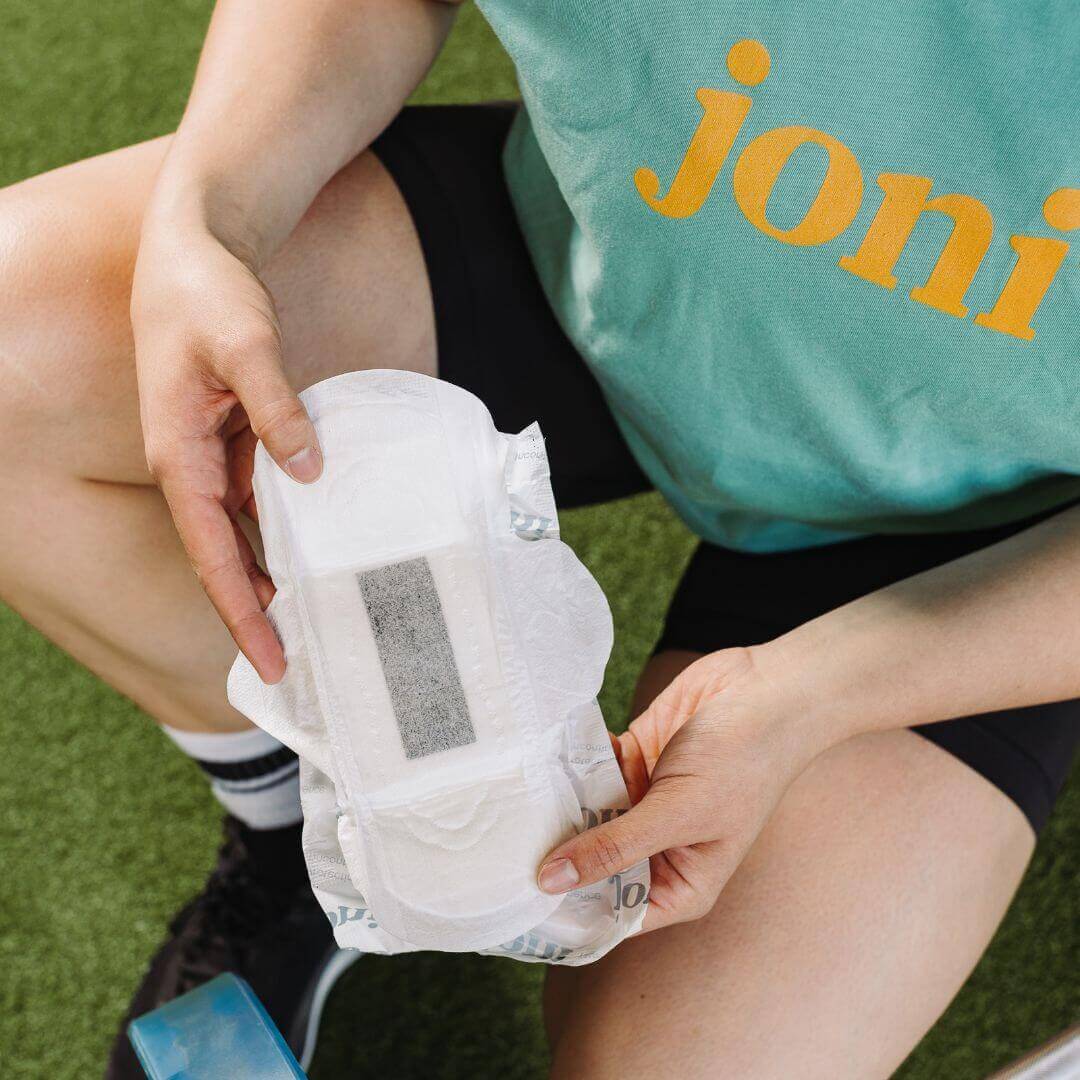 A person holding an organic bamboo incontinence pad, showcasing its ultra-thin and absorbent design.