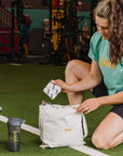 Woman at gym unpacking joni bamboo incontinence pads from tote bag for on-the-go protection.