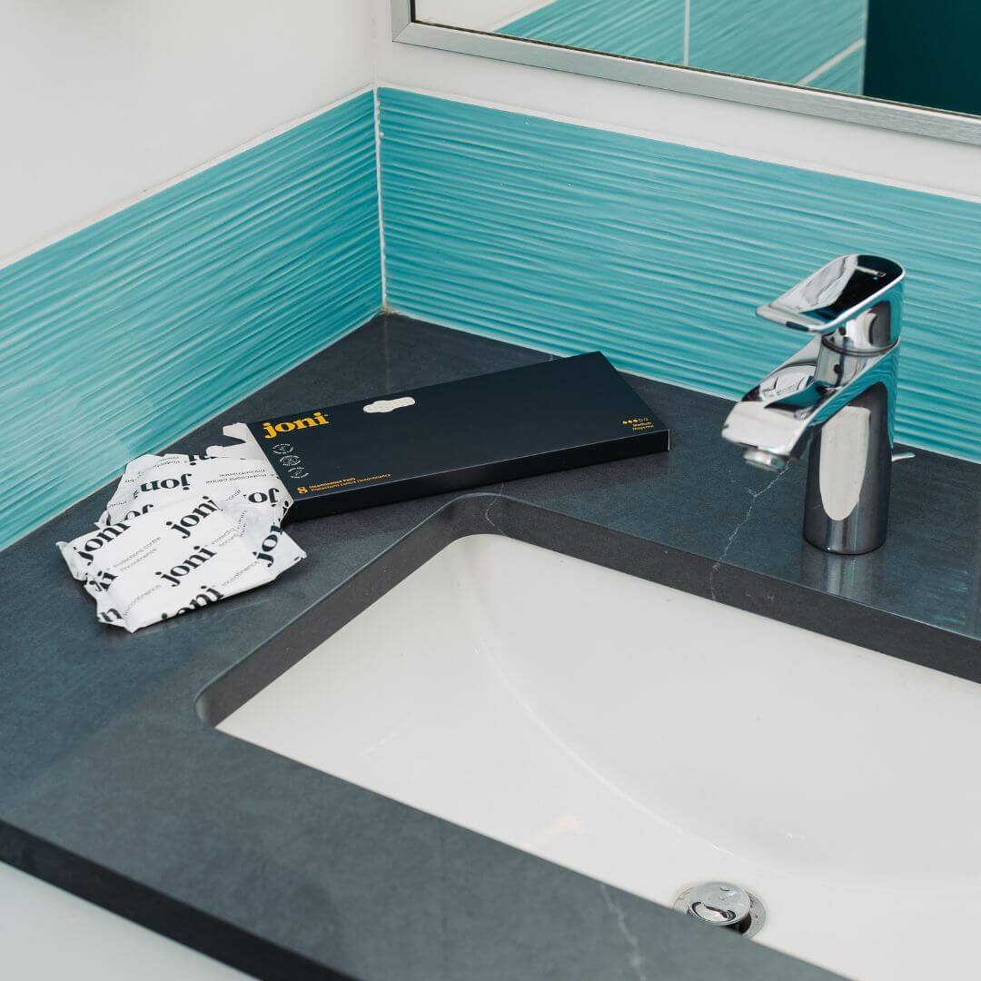 Bamboo incontinence pads by joni displayed on bathroom countertop next to a sink, highlighting absorbent and plant-based design.