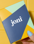 a hand with blue nail polish holds a joni mini box that contains three pads