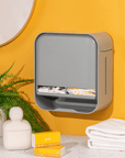 Wall-mounted joni Model A period pad and tampon dispenser in a yellow washroom with a plant