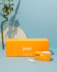 Yellow casepack of joni regular tampons for commercial washrooms with a blue background and bamboo