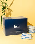 Blue bulk box of joni super pads on a yellow background with bamboo