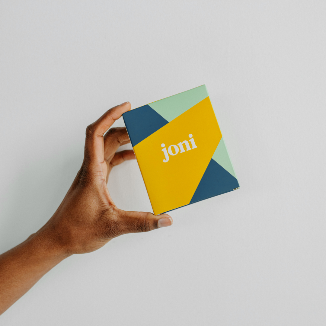 Person holding joni Mini Period Pad Pack in colorful eco-friendly packaging.