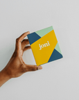 Person holding joni Mini Period Pad Pack in colorful eco-friendly packaging.