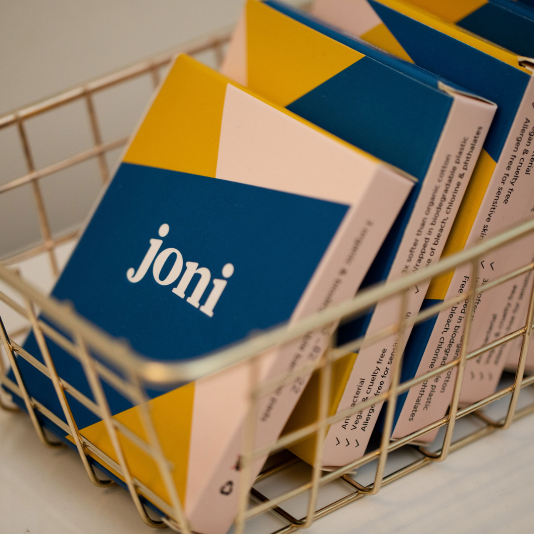 Basket of joni Mini Period Pad Packs with vibrant blue and yellow packaging for eco-friendly menstrual care.