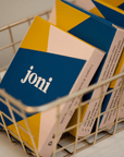 Basket of joni Mini Period Pad Packs with vibrant blue and yellow packaging for eco-friendly menstrual care.