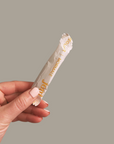Hand holding a regular applicator tampon wrapped in recyclable packaging, showcasing organic cotton product.