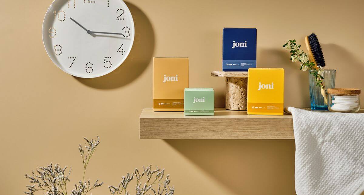 joni pads and tampons on a bathroom shelf with a clock on the wall