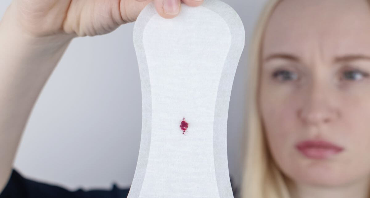 Concerned woman looks at blood-stained period pad