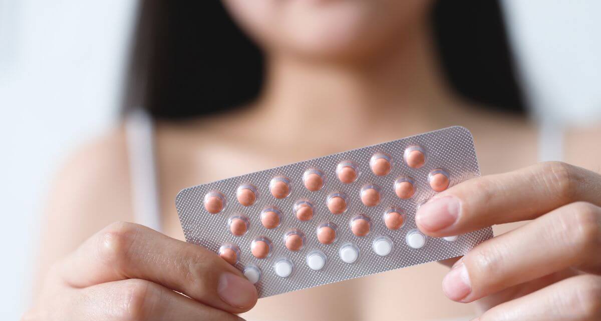 Woman holds a package of birth control pills as she contemplates stopping birth control