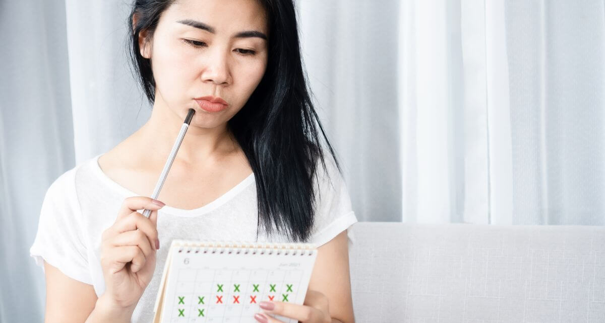 Woman looks at calendar to track her period 