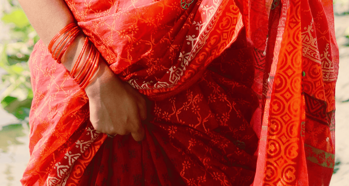 A woman in a red sari to illustration menstrual stigma in a south asian home