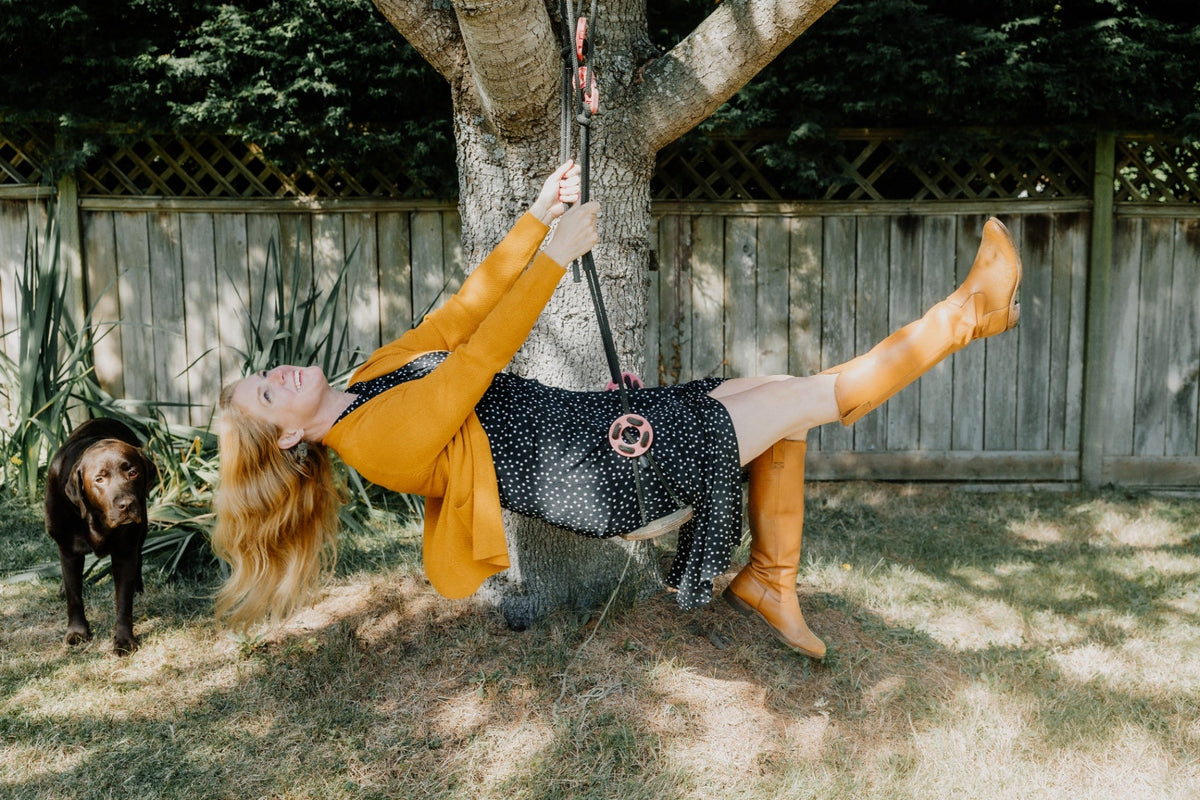 Founder of Hello Nila, Erin Beattie, in a yellow sweater on a swing