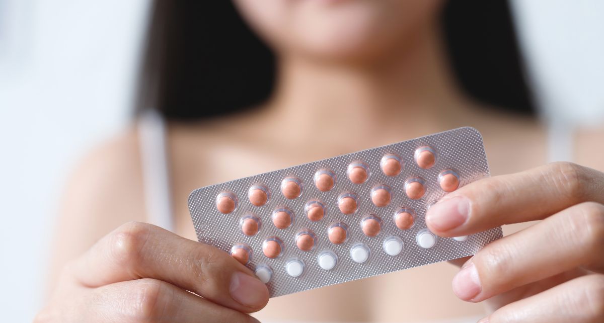 Close-up of a woman holding a blister pack of birth control pills, highlighting hormonal contraception options.