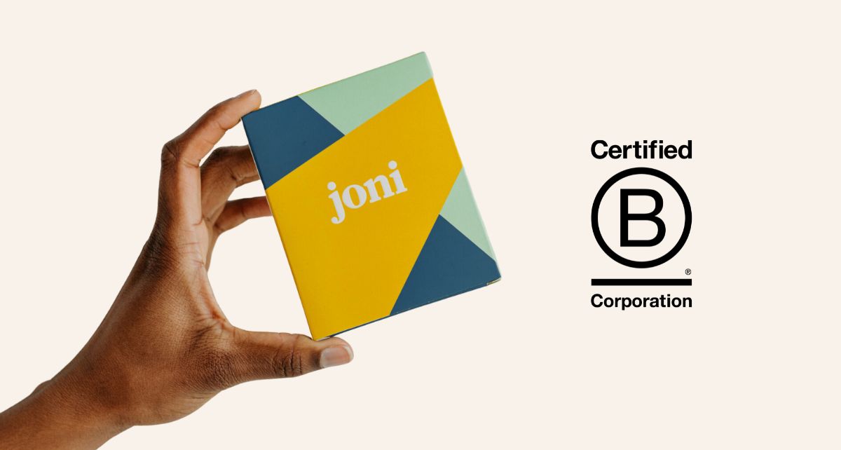 Person holding joni's B Corp certified organic period care box, showcasing vibrant packaging and certification logo.