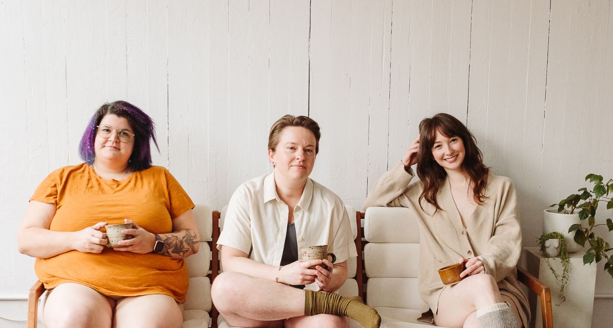 Three people who menstruate sit on a bench and look at the camera