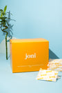 Yellow bulk box of joni regular pads with a blue background and a bamboo plant