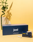 joni casepack of super tampons for commercial washrooms on a yellow background with bamboo